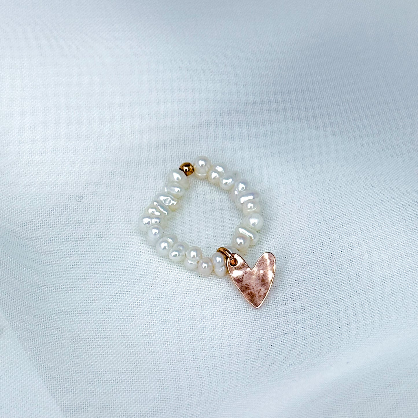 Anello elasticizzato perle tonde bianche irregolari con cuore battuto allungato pendente